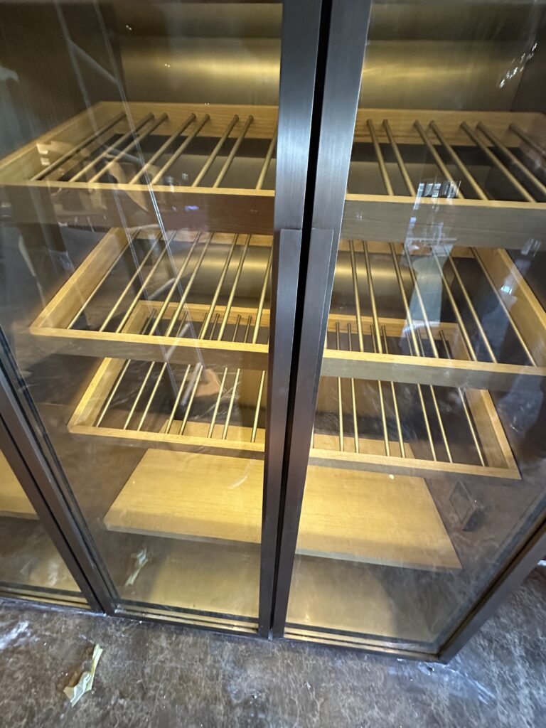 Close detail of antique brass shelving inside a glazed metal cabinet