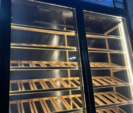 Close-up of illuminated WINES signage panel above glass-door wine display cabinet