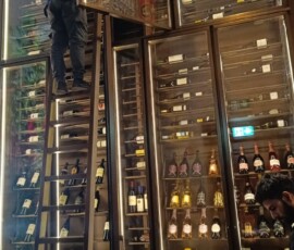 BartechCo technician commissioning the restaurant wine wall on site, upper cabinet door open