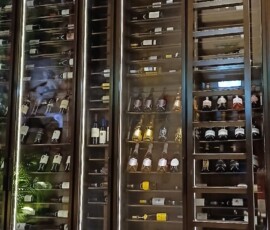Wide view of bespoke restaurant wine wall with backlit signage panel and stocked champagne and wine bays